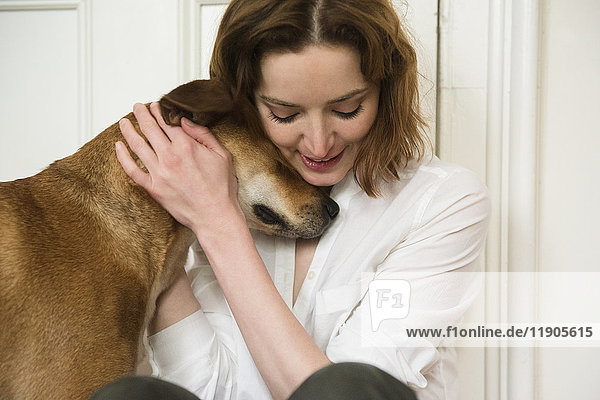 Kaukasische Frau umarmt Hund