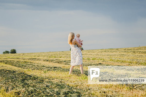 Mutter trägt ihre kleine Tochter auf einem Feld