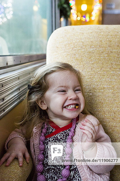Kaukasisches Mädchen grinst am Fenster im Zug