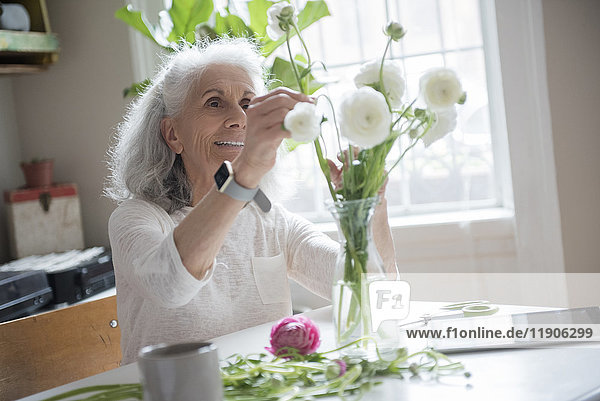 Ältere Frau arrangiert Blumen