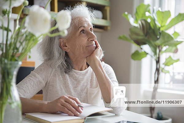 Nachdenkliche ältere Frau schreibt in ein Tagebuch