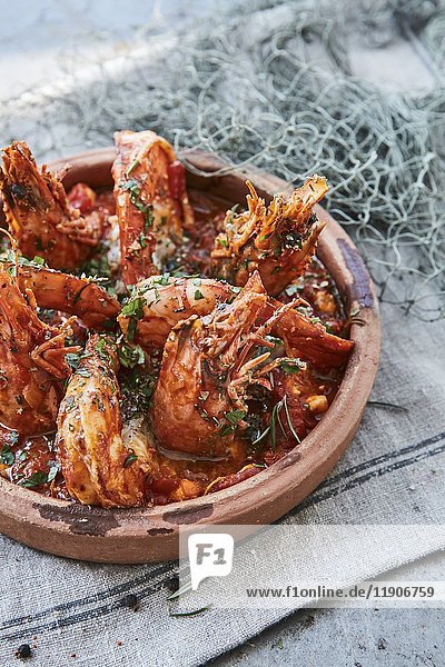 Gambas with garlic and tomato sauce and herbs in a rustic serving dish