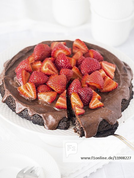 Veganer Schokoladenkuchen ohne Mehl (glutenfrei) mit Mohn und Schokoladenglasur  serviert mit Erdbeeren