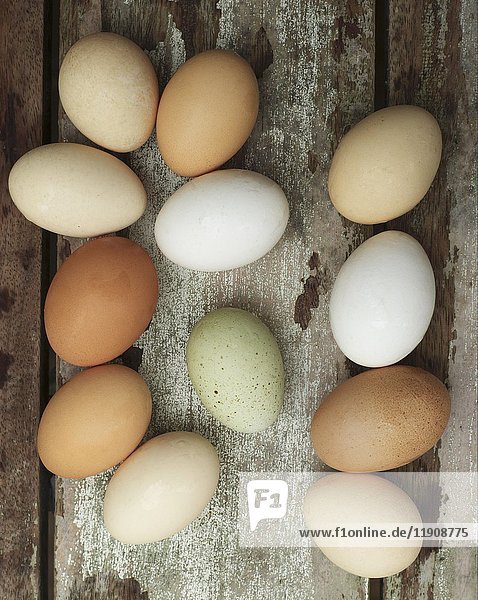 Verschiedenfarbige frische Eier auf einem hölzernen Hintergrund