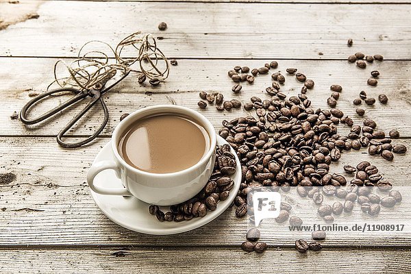 Weißer Kaffee in einer Tasse und Kaffeebohnen - mit Schere und Schnur im Hintergrund
