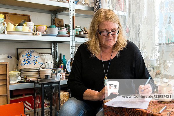 Tilburg Netherlands. Mature adult caucasian woman maintaining her own shop in vintage household items and furniture.