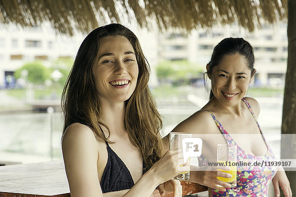 Frauen trinken Saft in der Cabana neben dem Schwimmbad