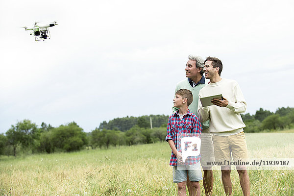 Mehrgenerationen-Familie spielt mit Drohne im Feld