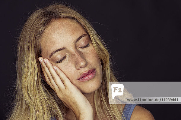 Young woman resting cheek on hand  eyes closed  portrait