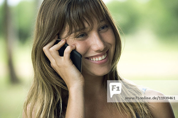 Junge Frau spricht am Handy und lächelt