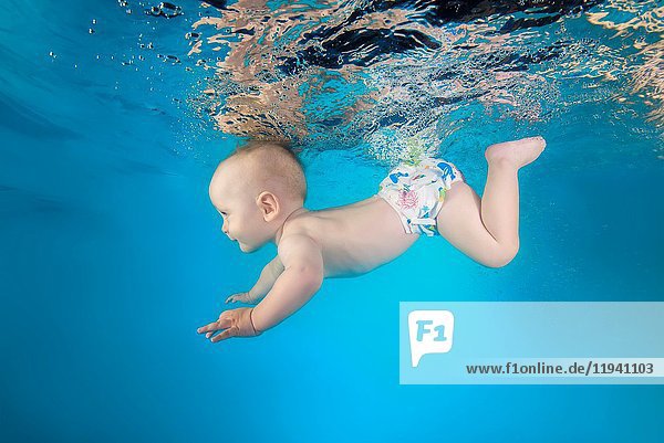 Little boy learns to dive underwater in the pool.