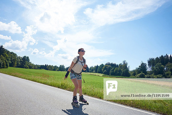 Deutschland Bayern Frau fährt Inlineskates auf einer Landstraße