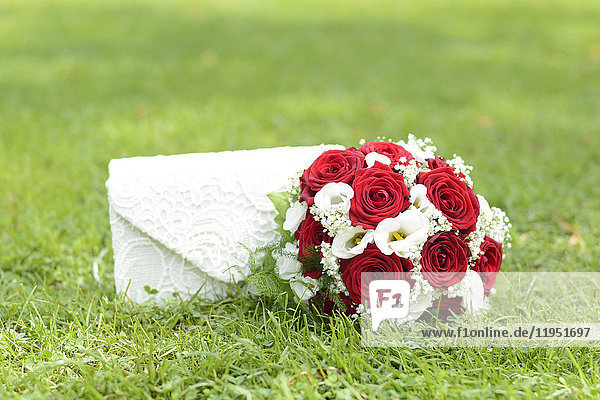 Bridal bouquet and handbag on lawn