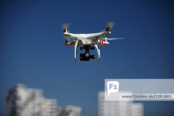 Drone flying in blue sky near apartment blocks