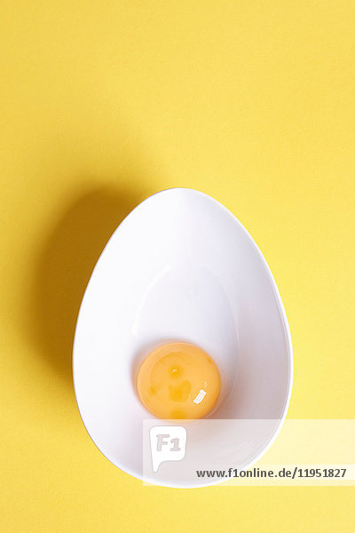Overhead view of egg yolk in oval bowl on yellow background