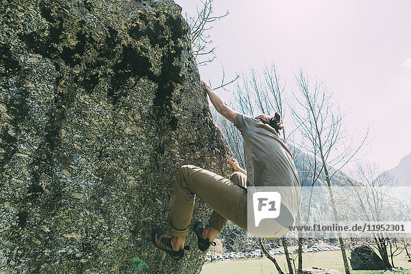 Young male boulderer climbing boulder  Lombardy  Italy