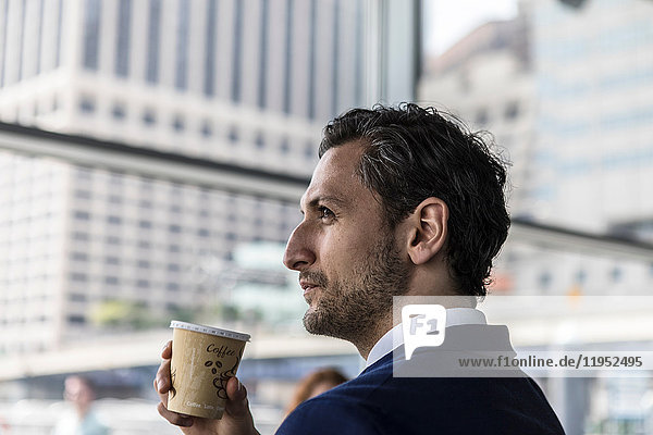 Young businessman in city with takeaway coffee  New York  USA