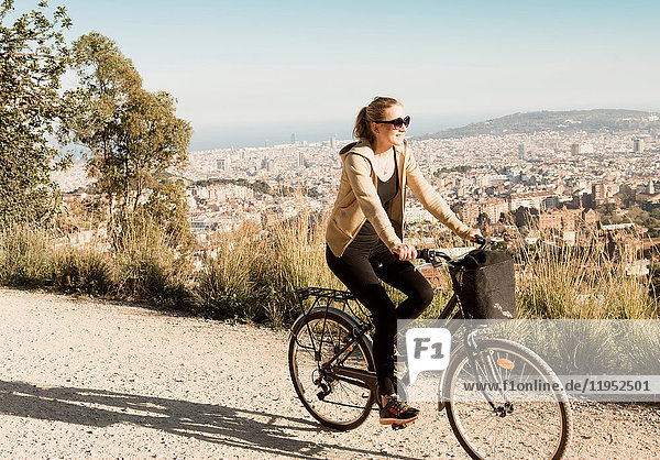 Frau beim Sightseeing auf dem Fahrrad  Stadt im Hintergrund  Barcelona  Katalonien  Spanien