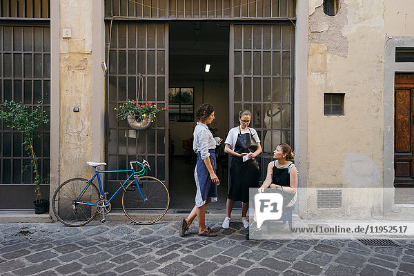 Drei Juwelierinnen machen eine Kaffee- und Zigarettenpause vor dem Eingang der Schmuckwerkstatt