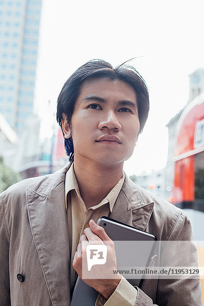 Junger Mann geht draußen spazieren  trägt ein digitales Tablett  Nahaufnahme