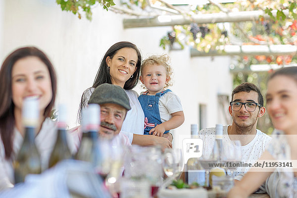 Family having lunch outdoors under grapevine trellis
