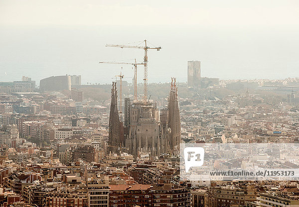 Erhöhter,  dunstiger Blick auf das Stadtbild mit La Sagrada Familia und Baukränen,  Barcelona,  Spanien