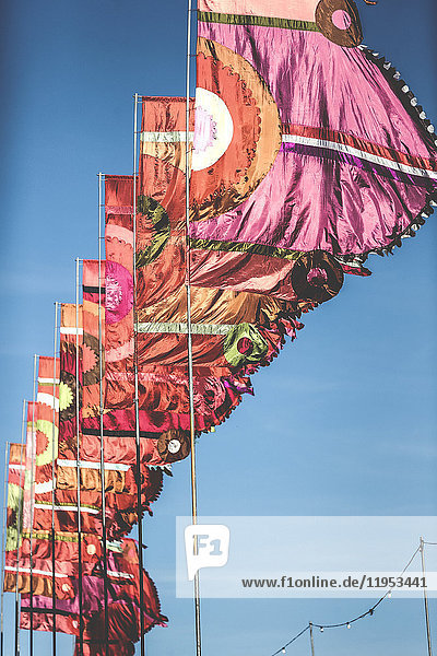 Tiefblick auf eine Reihe von rosa und orangefarbenen Bannern  Flaggen  die bei einem Sommer-Musikfestival in der Brise flattern.