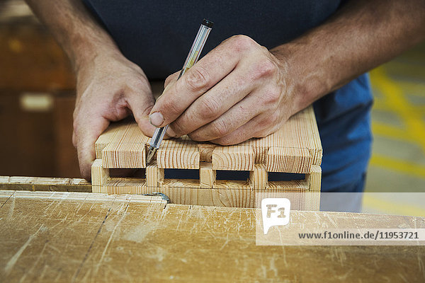 Nahaufnahme einer Person  die in der Werkstatt eines Bootsbauers arbeitet und zwei Holzstücke zusammenfügt.
