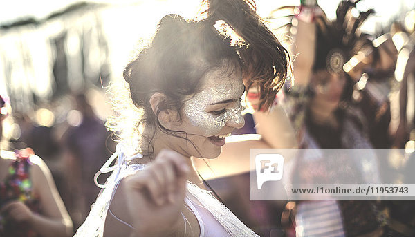 Junge Frau bei einem Sommer-Musikfestival,  die in der Menge tanzt.