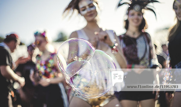 Revellers at a summer music festival large soap bubbles in foreground.