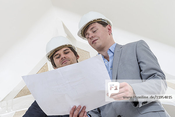 Zwei Ingenieure oder Architekten diskutieren über ein Projekt auf einer Baustelle in weißer Umgebung