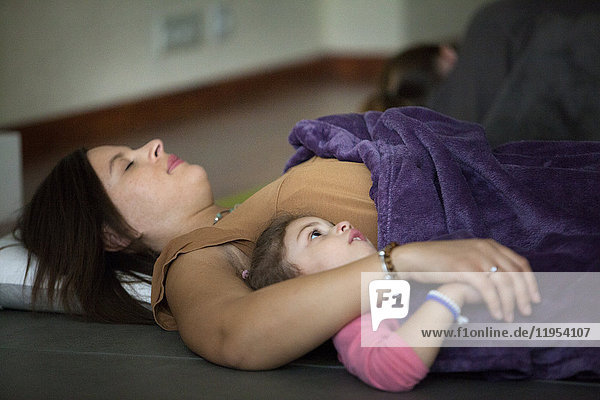Reportage über eine Eltern-Baby-Yoga-Sitzung. Während der Sitzung demonstriert die Lehrerin verschiedene Übungen  die leicht zu Hause nachgemacht werden können. Diese Übungen ermöglichen es den Teilnehmern  innezuhalten  sich zu entspannen und diesen Moment mit ihrem Baby zu teilen.