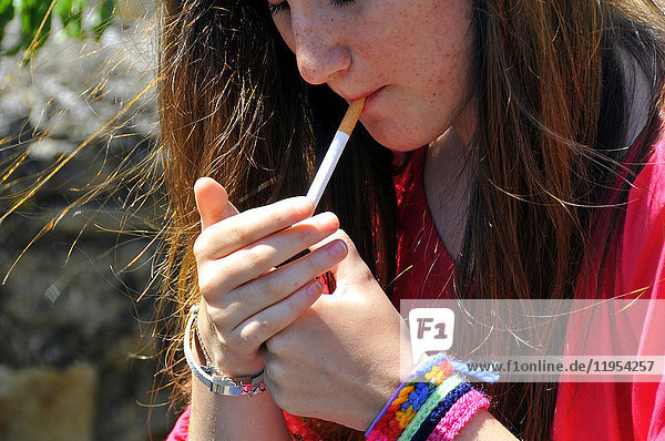 Ein Jugendlicher zündet sich eine Zigarette an.