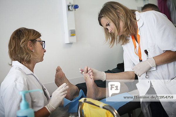 Reportage über die Fußsprechstunde für Diabetiker in einem Krankenhaus in Savoyen  Frankreich. Diese Sprechstunden werden von einem spezialisierten Team durchgeführt und sind der Behandlung und Nachsorge von Fußverletzungen bei Diabetikern gewidmet. Der Diabetologe und der Podologe untersuchen den Fuß eines Patienten.