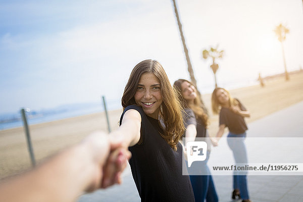 Fröhliche junge Frauen halten ihre Hände im Freien.