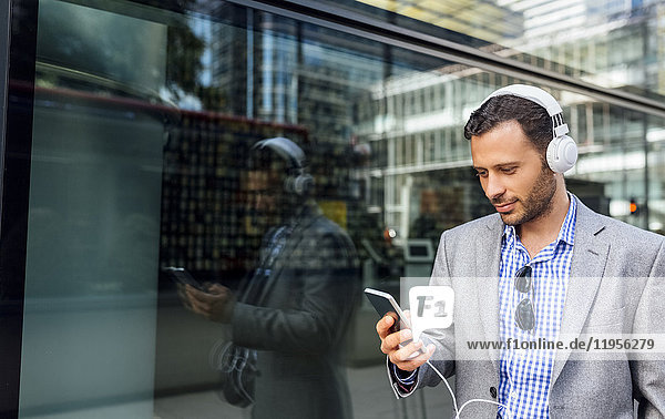 Businessman listening to music with headphones in the city