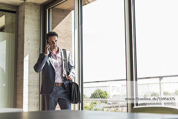 businessman standing by window  making a phone call