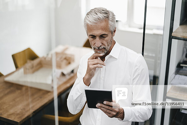 Mature businessman looking at tablet in office