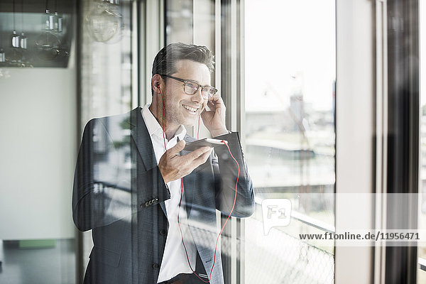 Portrait of confident businessman on the phone looking through window