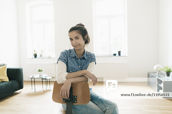 Porträt einer Frau  die zu Hause auf einem Stuhl sitzt.