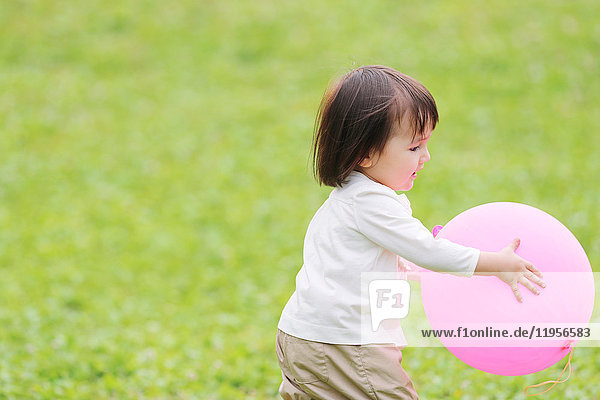 Gemischtrassiges junges Mädchen spielt mit Luftballon im Park