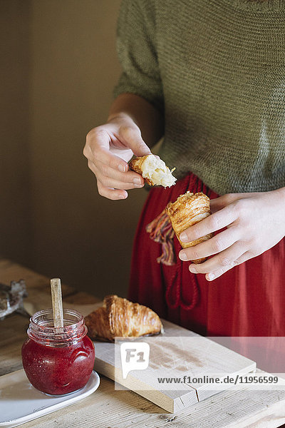 Nahaufnahme einer Frau  die hausgemachte Croissants mit Marmelade probiert.