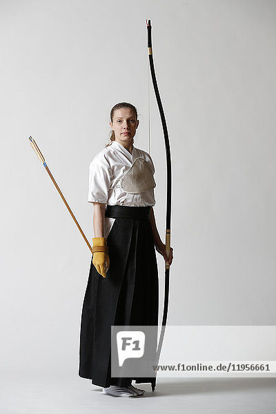 Caucasian woman practicing traditional Kyudo Japanese archery on white background