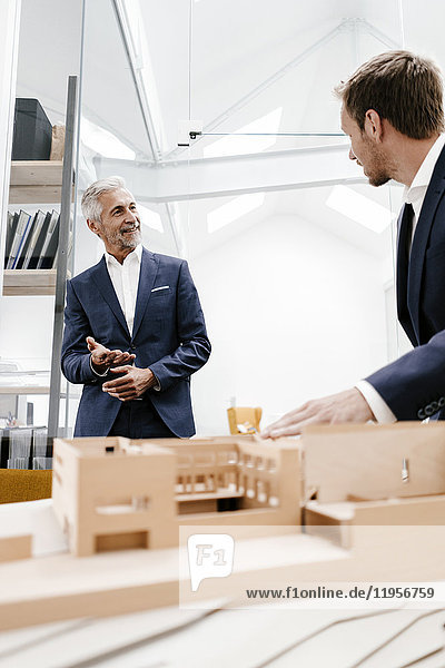 Two businessmen with architectural model in office