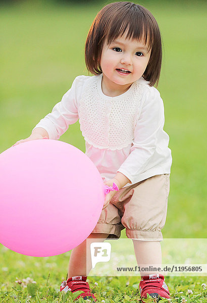 Gemischtrassiges junges Mädchen spielt mit Luftballon im Park