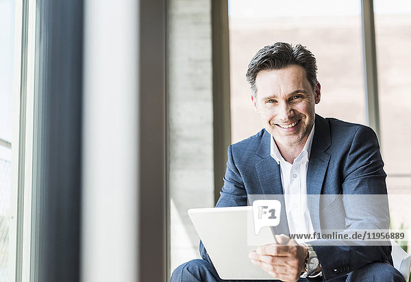 Portrait of smiling businessman with tablet