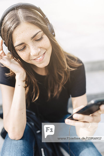 Smiling young woman listening to music outdoors