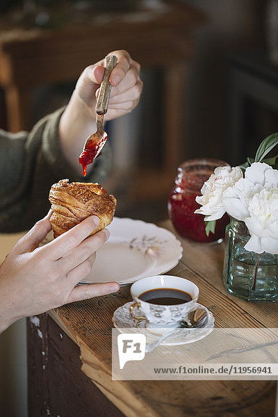 Close-up of woman tasting homemade croissants with jam