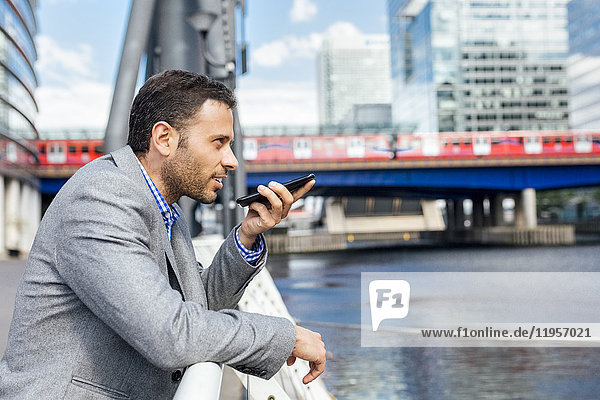 Geschäftsmann sendet Sprachnachrichten mit seinem Smartphone in der Stadt
