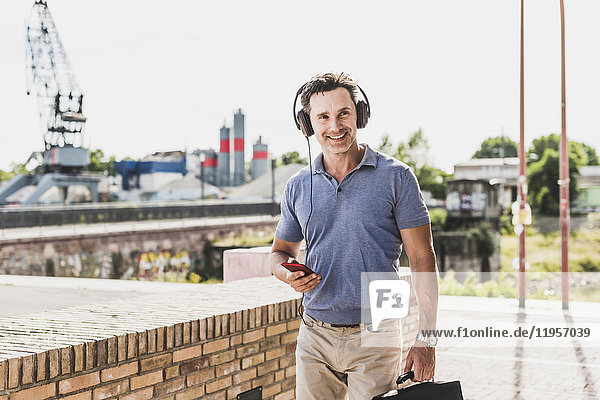 Geschäftsmann zu Fuß in der Stadt  mit Smartphone und Kopfhörer